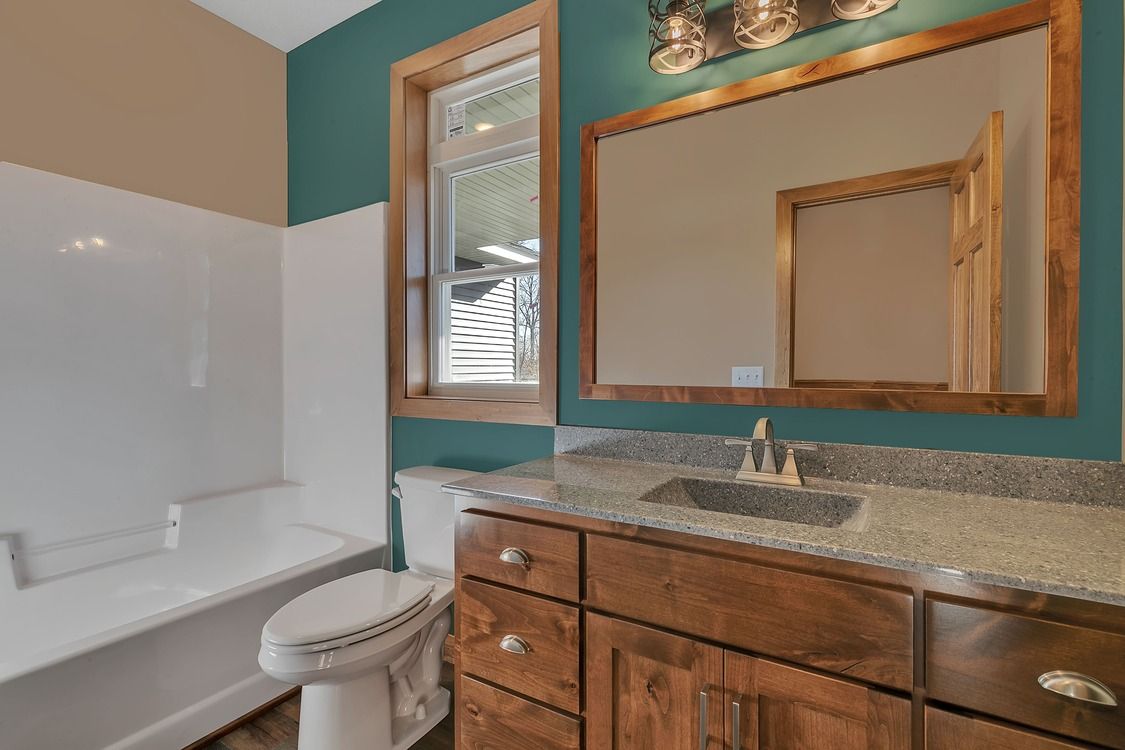 A bathroom with a toilet , sink , and mirror.
