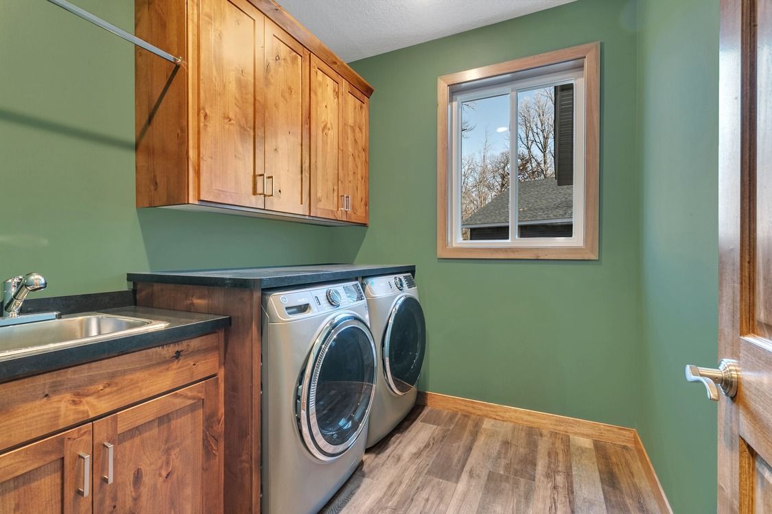 A laundry room with a washer and dryer , sink , and window.