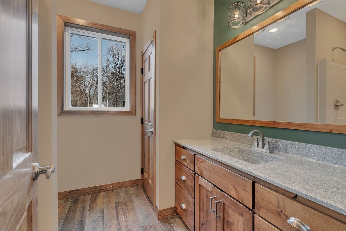 A bathroom with a sink , mirror and window.