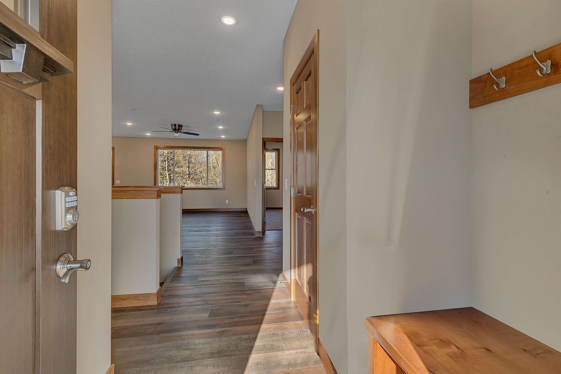 A hallway in a house with hardwood floors and a wooden bench.
