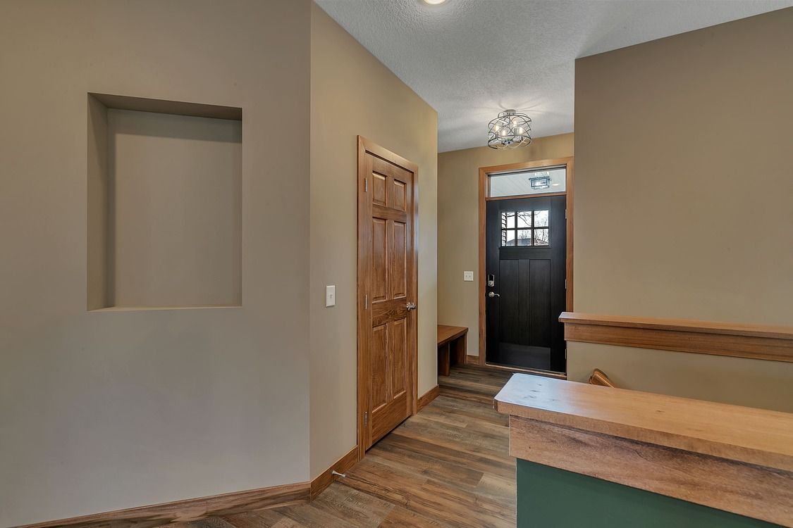 A hallway with a wooden floor and a black door in a house.