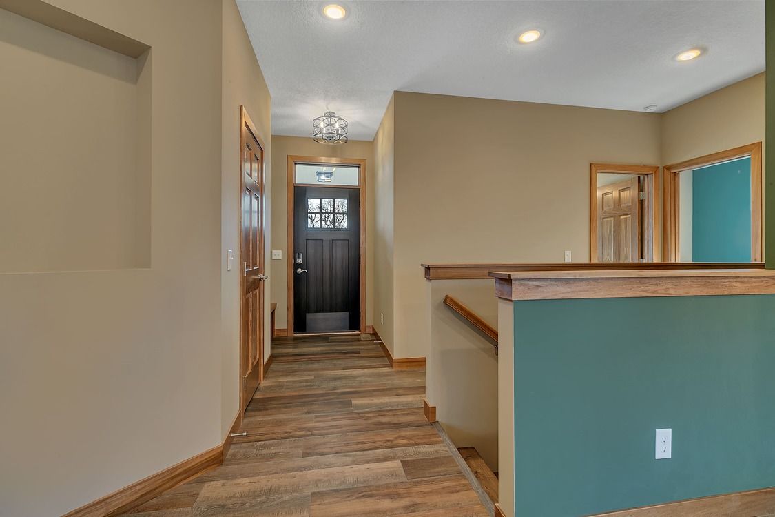 A hallway with wooden floors and a black door in a house.