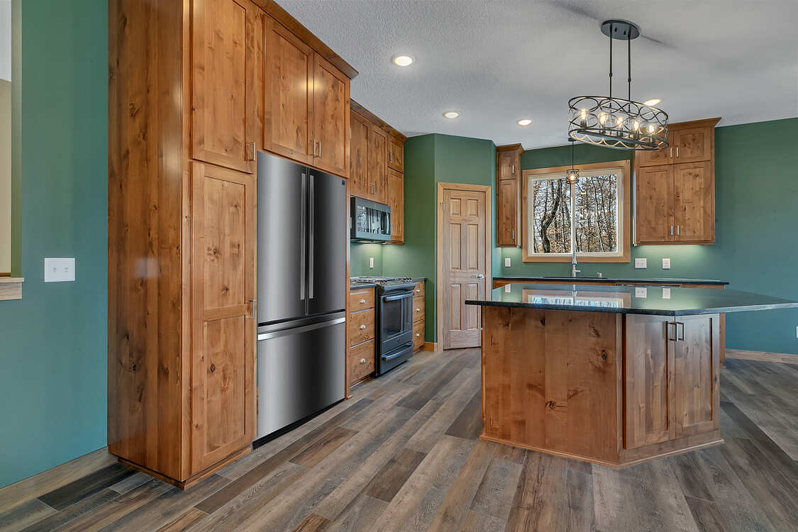A kitchen with wooden cabinets , stainless steel appliances , and a large island.