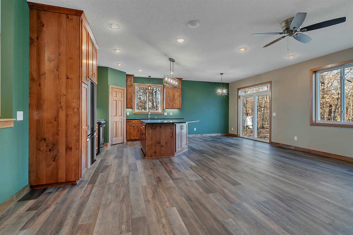 A large empty room with hardwood floors and a ceiling fan.