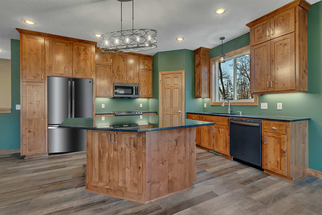 A kitchen with wooden cabinets , stainless steel appliances , and a large island.