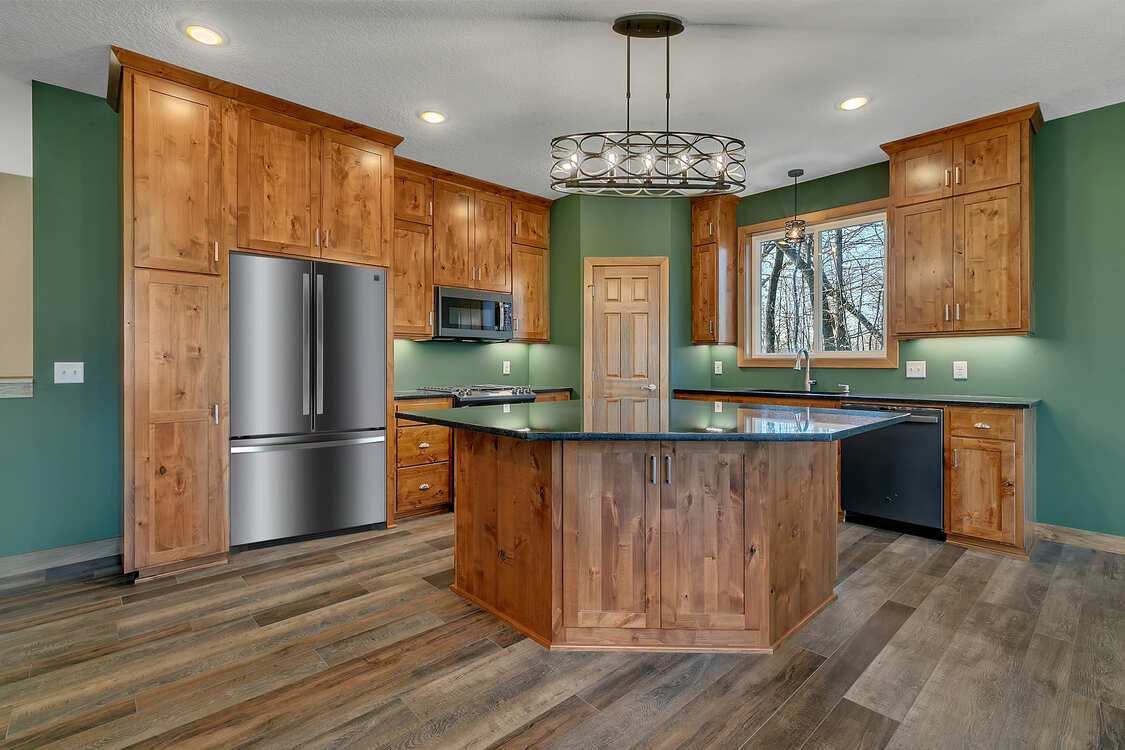 A kitchen with wooden cabinets , stainless steel appliances , and a large island.