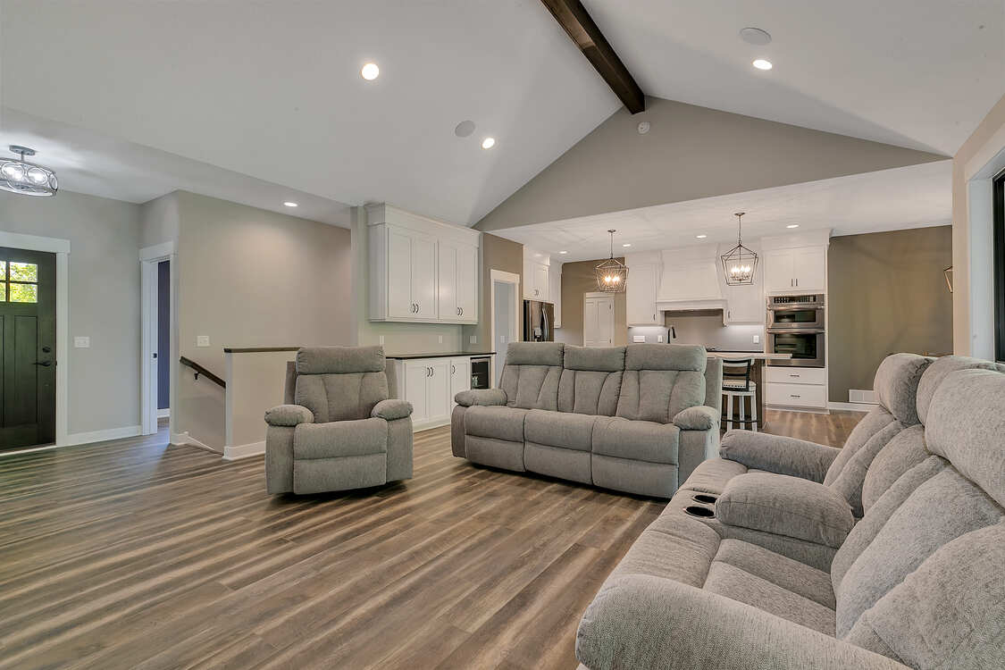 A living room with a couch , chairs and a vaulted ceiling.