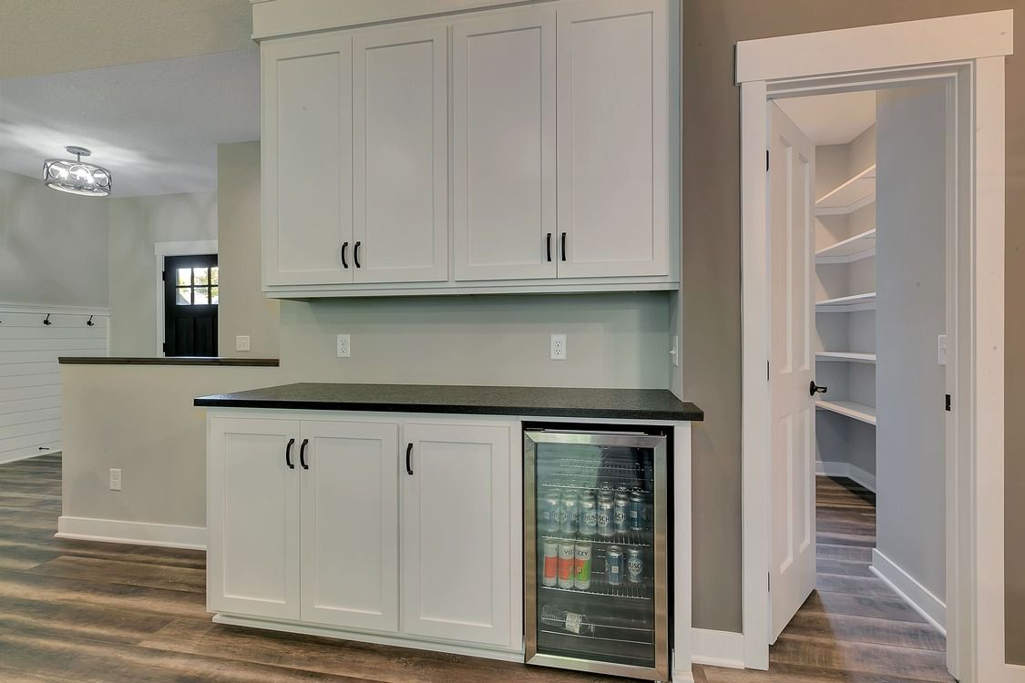 A kitchen with white cabinets and a refrigerator.