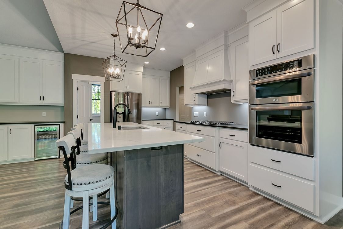 A kitchen with white cabinets , stainless steel appliances , and a large island.