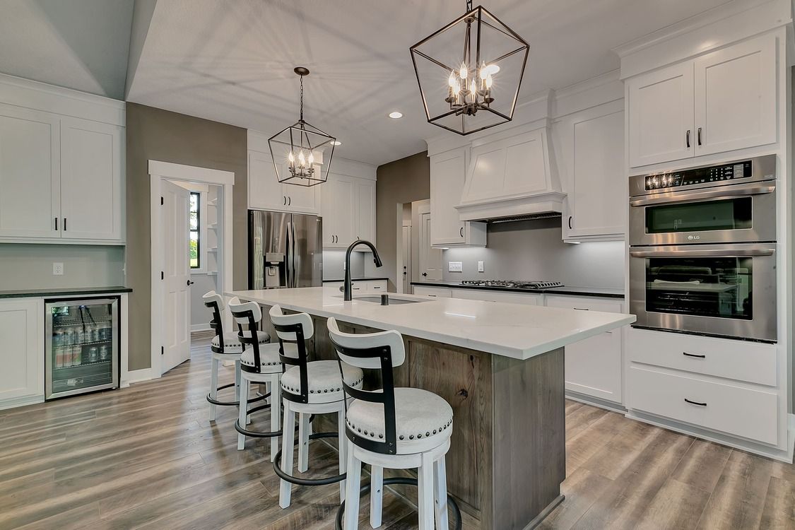 A kitchen with white cabinets , stainless steel appliances , and a large island.