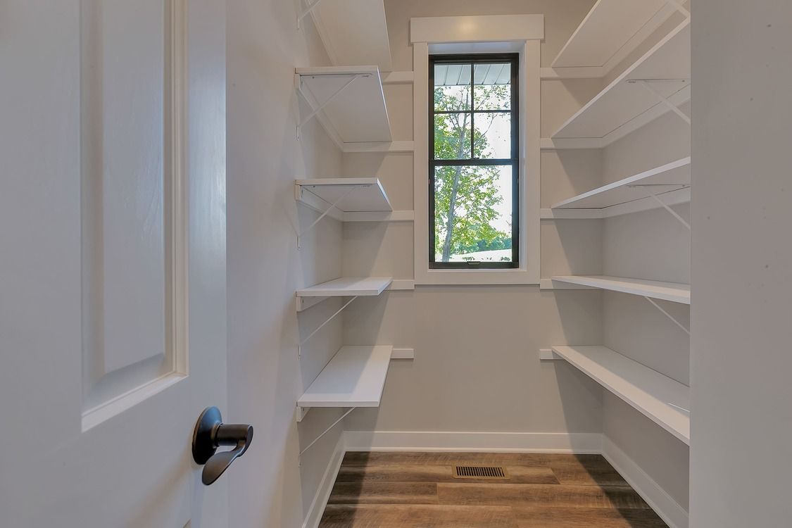 A walk in closet with shelves and a window.