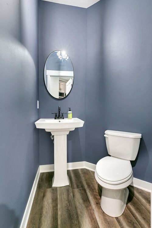 A bathroom with a toilet , sink and mirror.