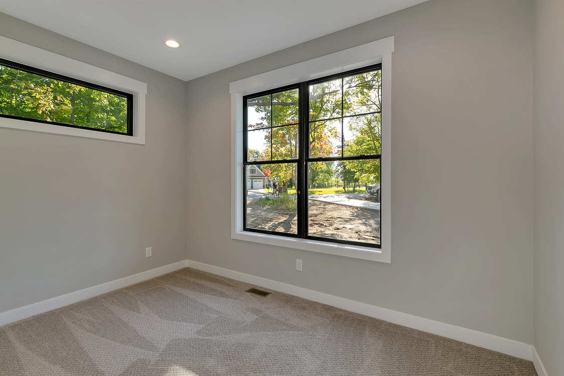 An empty room with two windows and a carpeted floor.