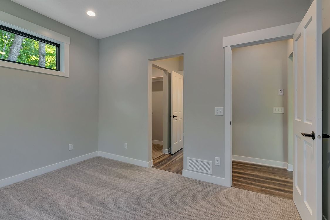 An empty room with a carpeted floor and a window.