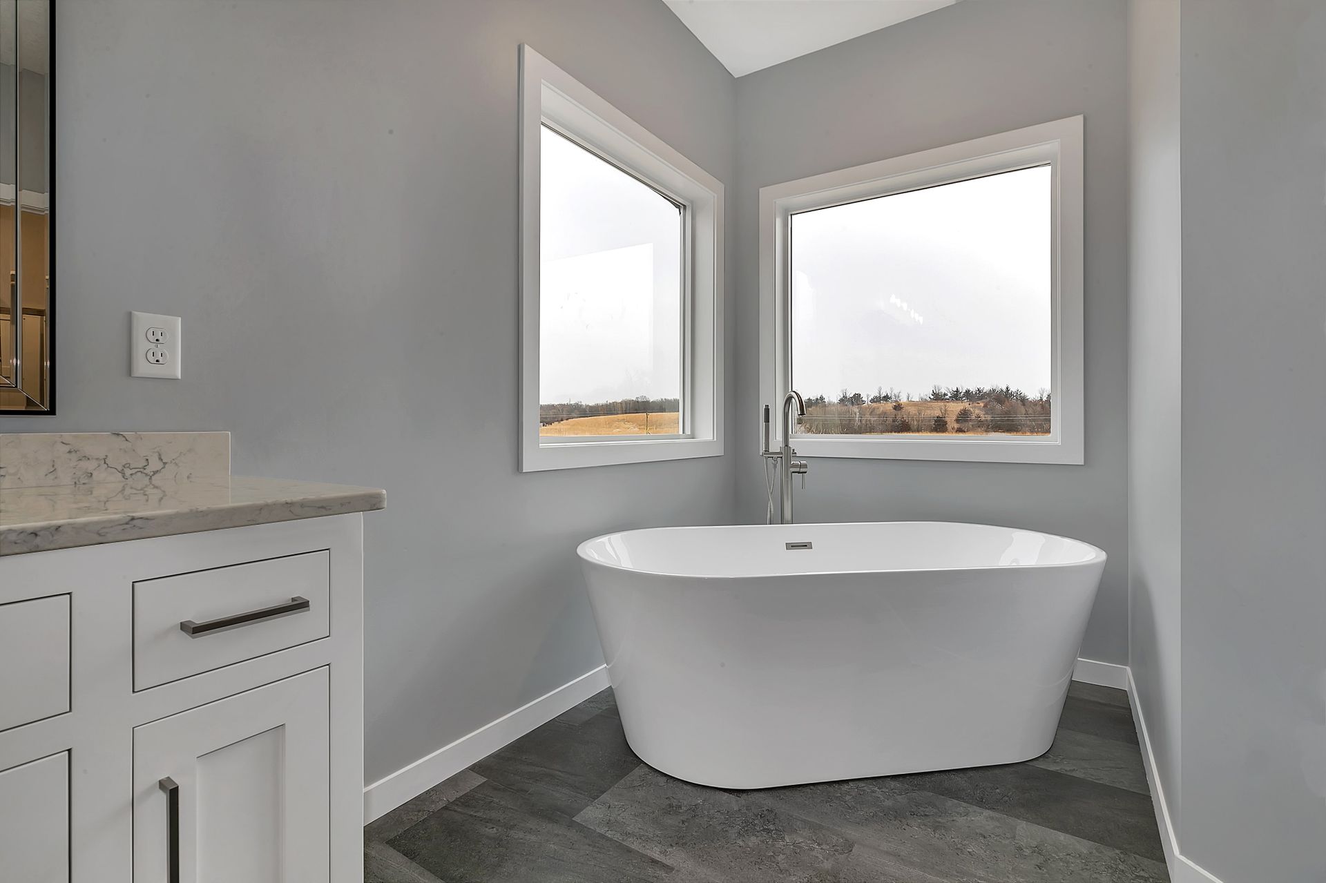 A bathroom with a bathtub and two windows.