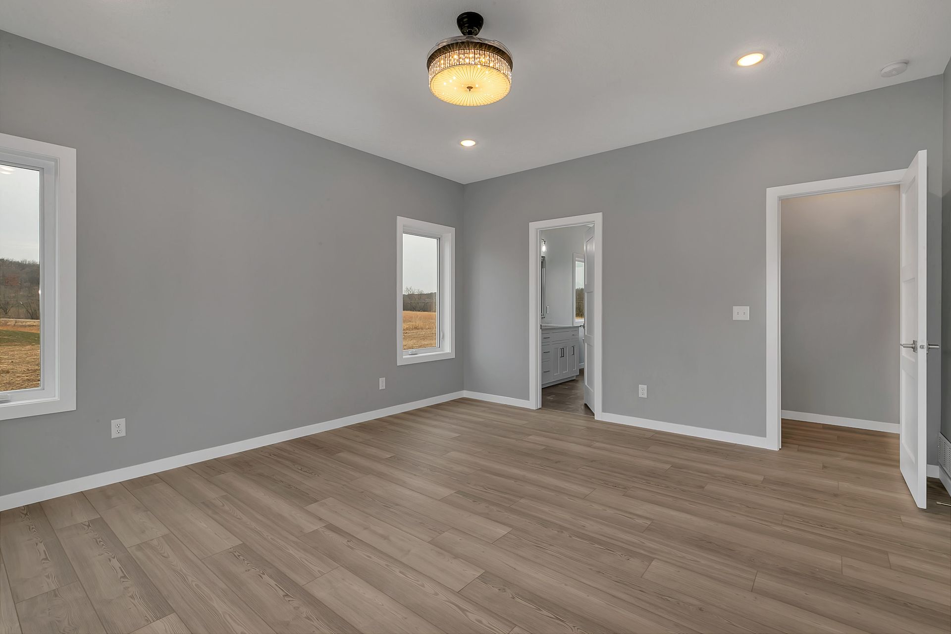 A large empty room with hardwood floors and gray walls.