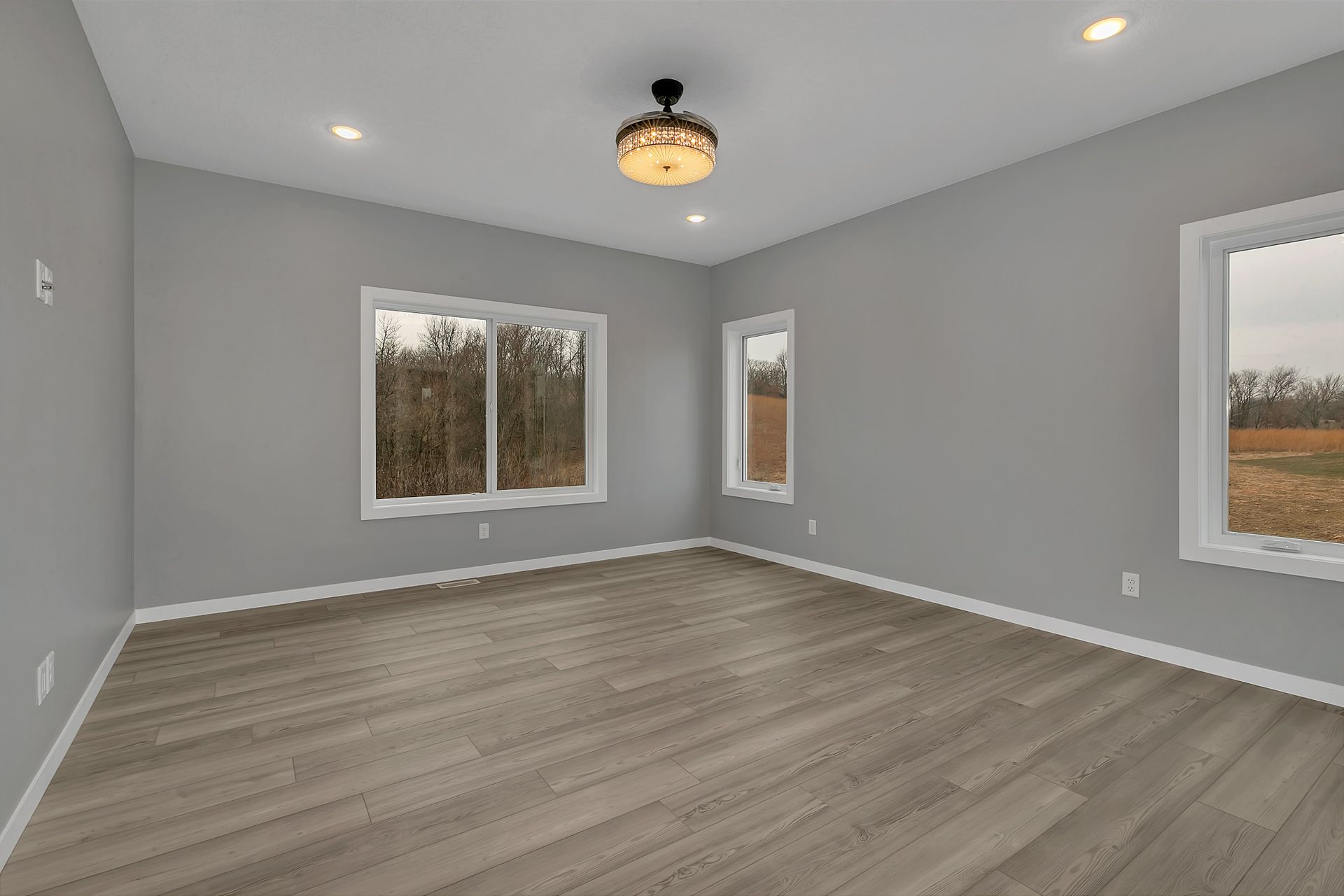A large empty room with hardwood floors and a ceiling fan.