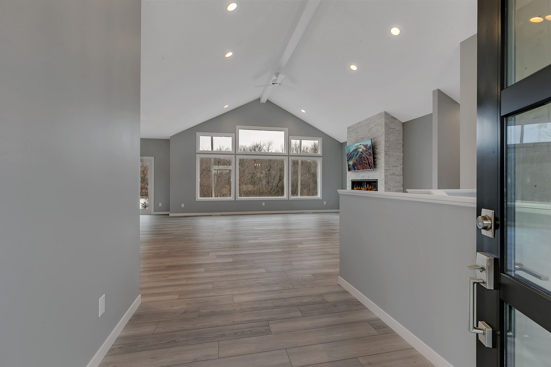 A hallway in a house with hardwood floors and a vaulted ceiling.