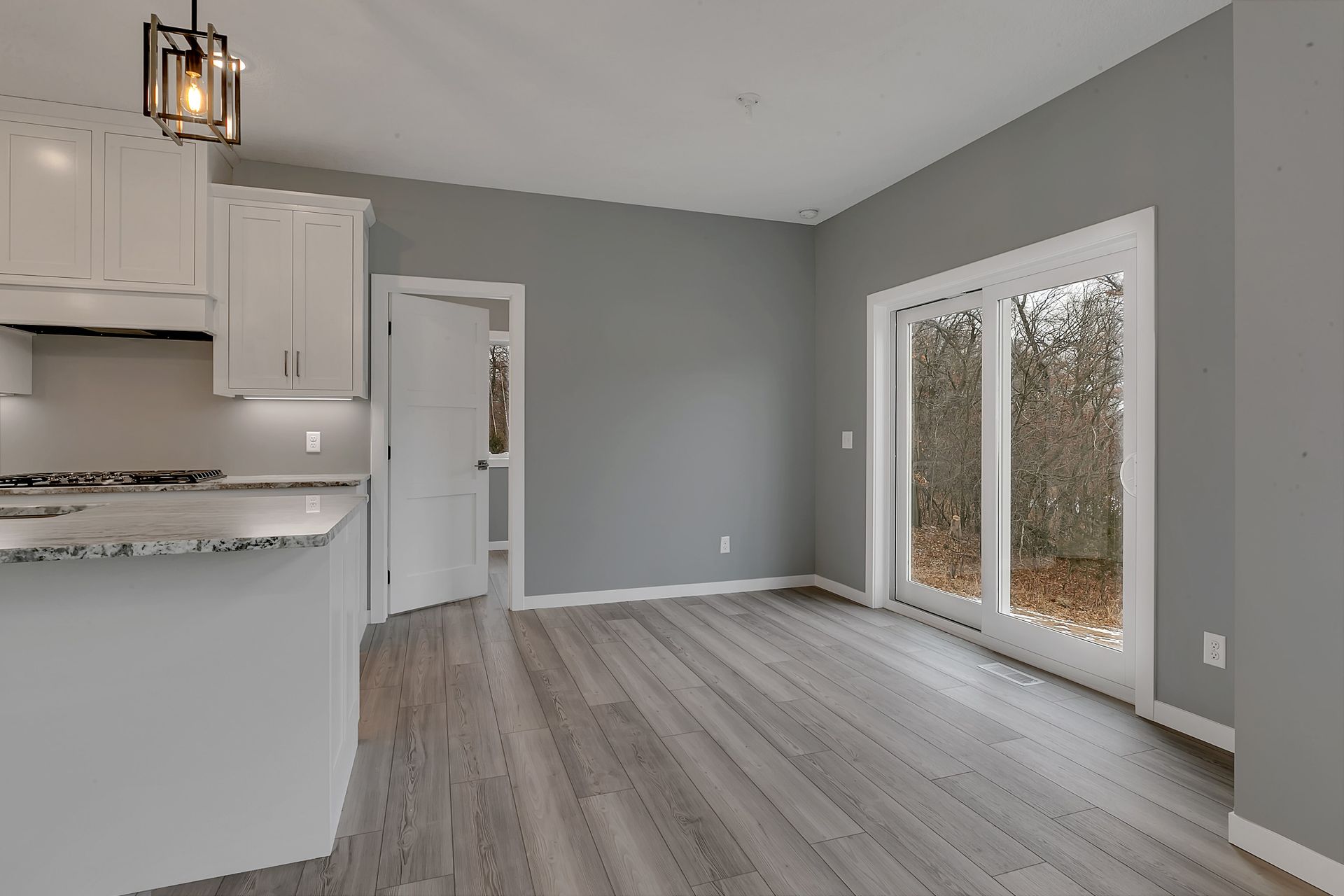An empty living room with hardwood floors and sliding glass doors.