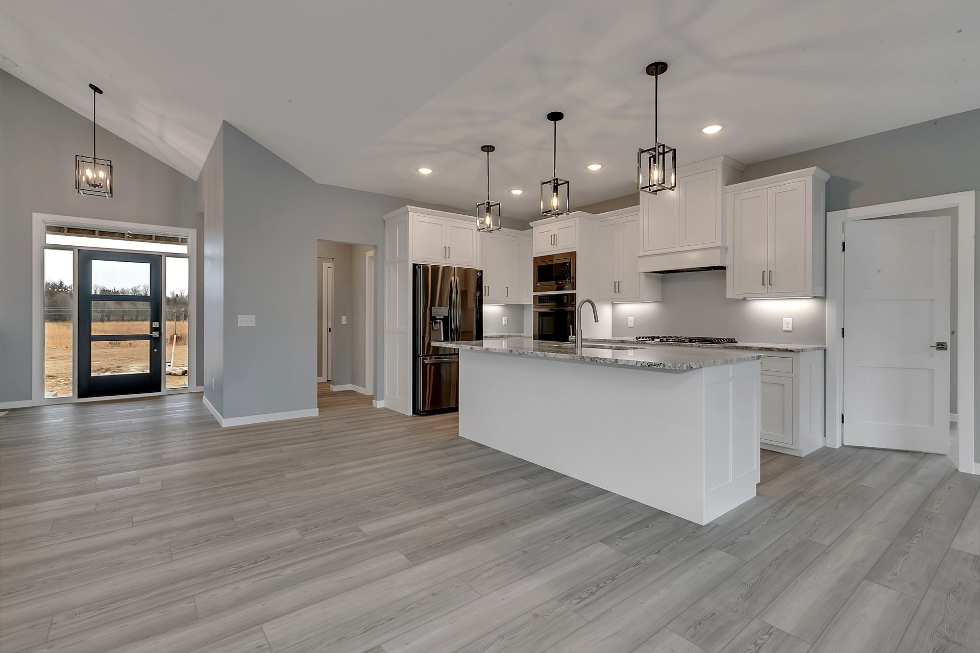 A kitchen with white cabinets and stainless steel appliances in a new home.