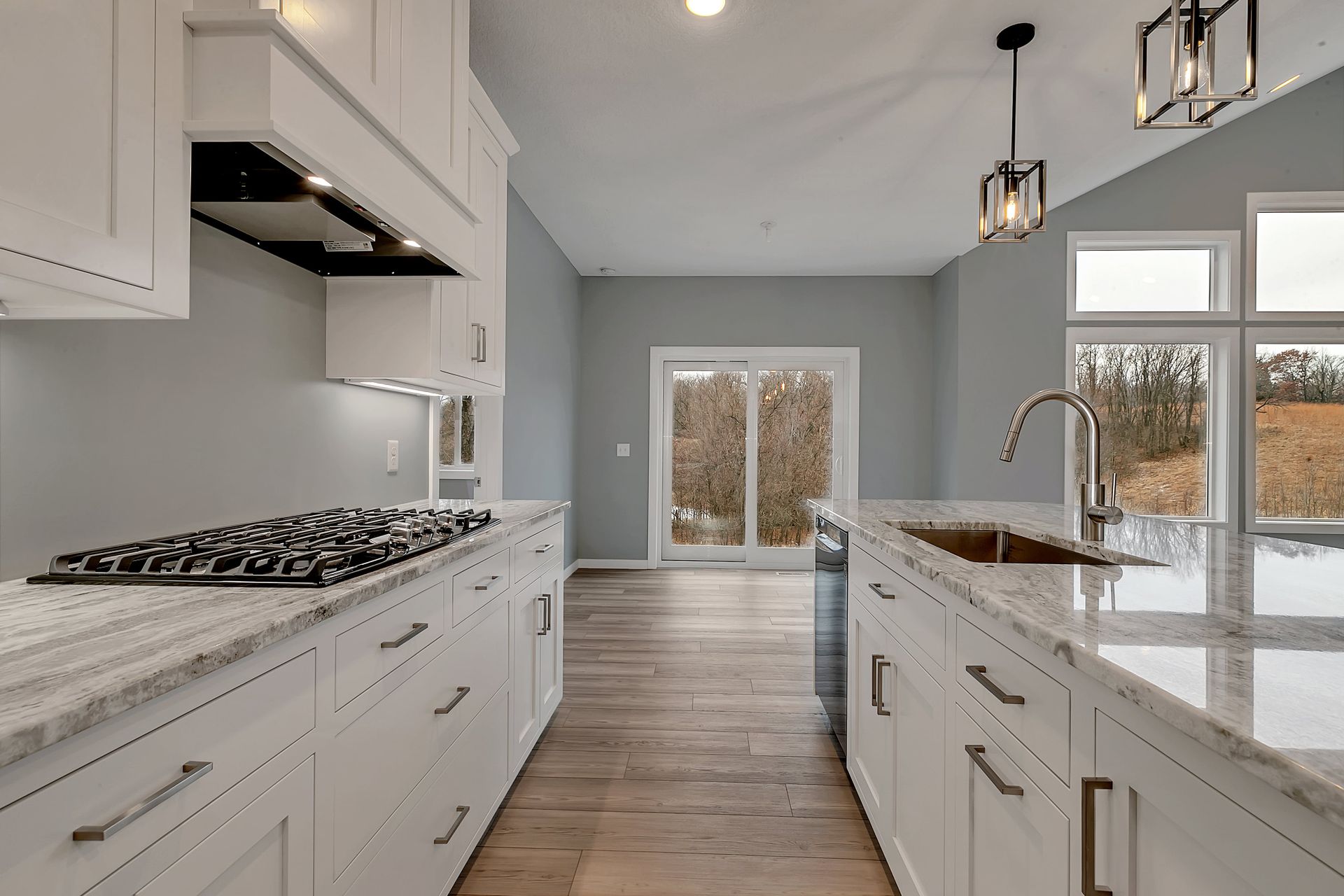 A kitchen with white cabinets , granite counter tops , and a stove top oven.