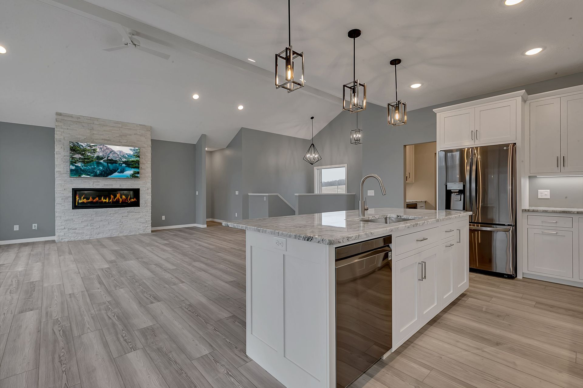 A kitchen with white cabinets , granite counter tops , stainless steel appliances and a large island.