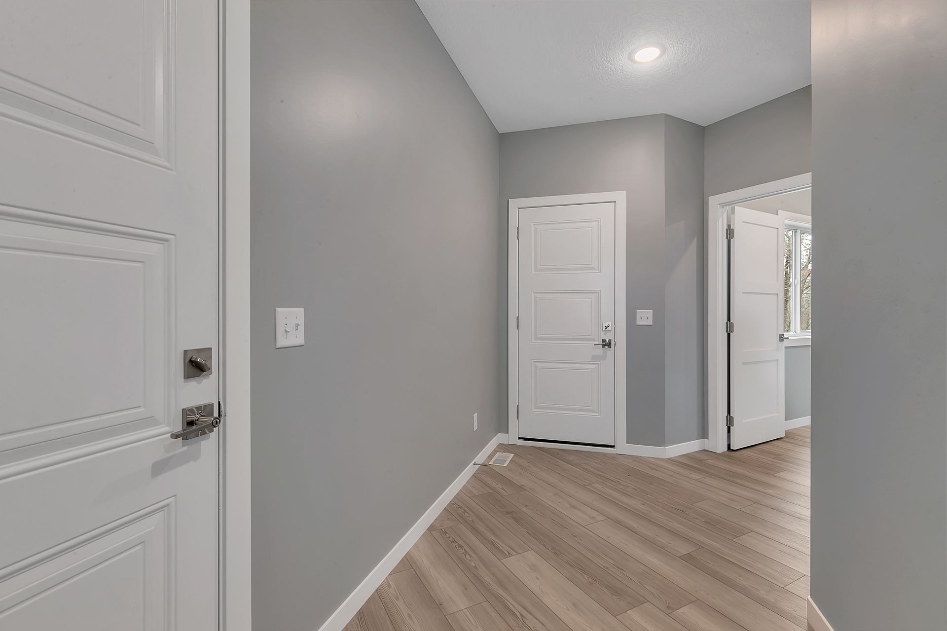 An empty hallway with hardwood floors and gray walls.