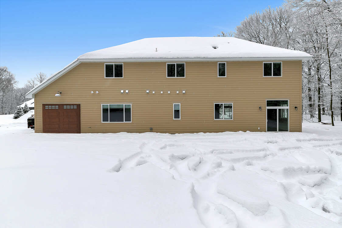A large house with a garage is covered in snow.