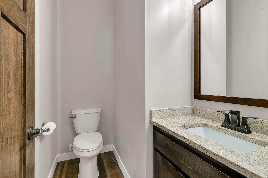 A bathroom with a toilet , sink and mirror.