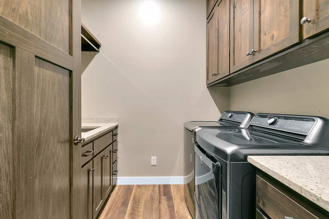 A laundry room with a washer and dryer and wooden cabinets.