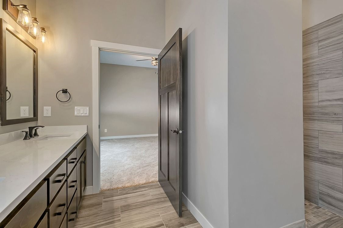 A bathroom with two sinks , a mirror , and a walk in shower.