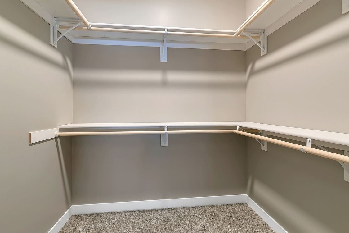 An empty walk in closet with a carpeted floor and shelves.