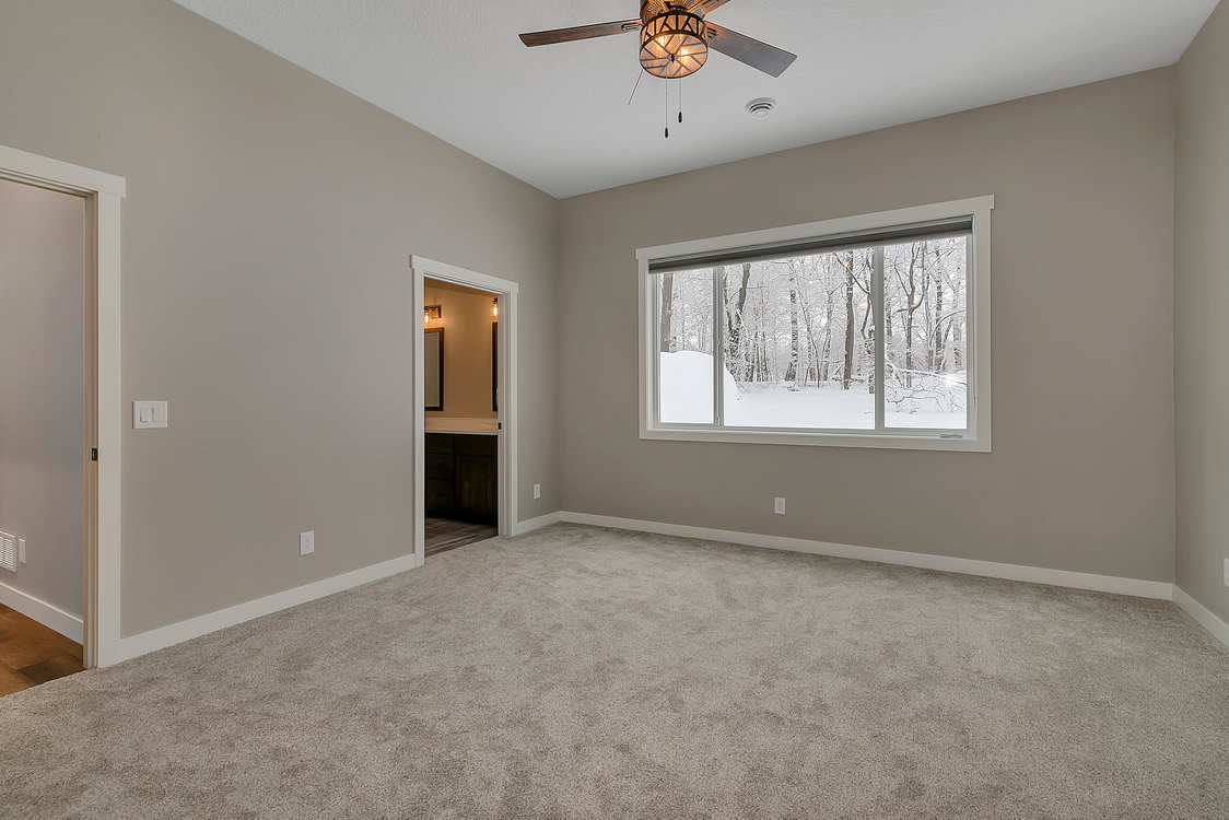 An empty bedroom with a ceiling fan and a large window.
