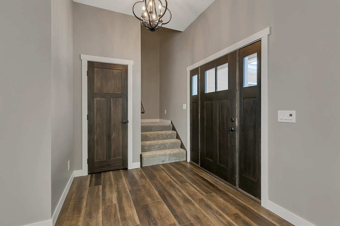 A hallway with wooden floors and stairs in a house.