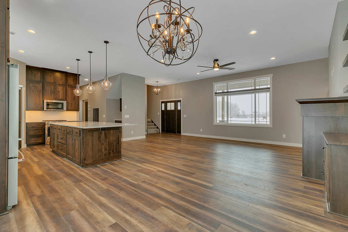 A large empty room with hardwood floors and a chandelier hanging from the ceiling.