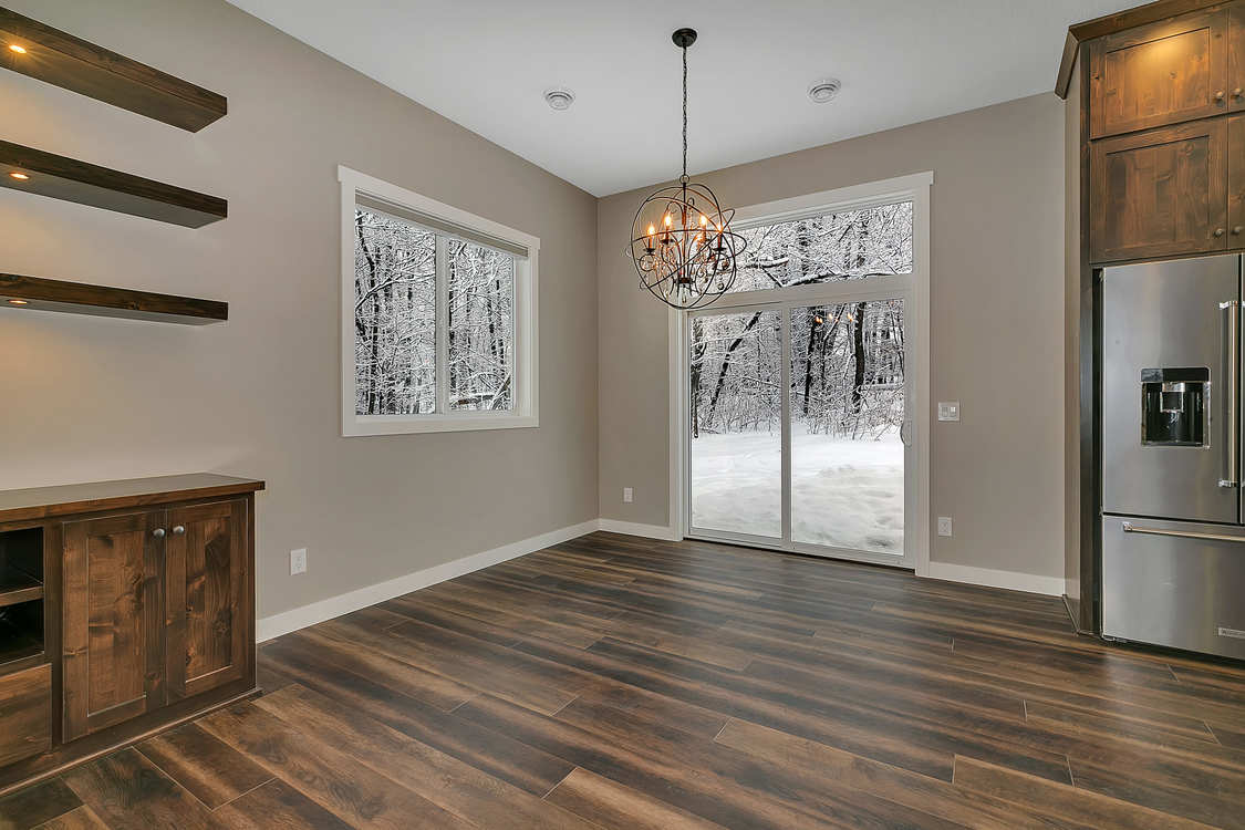 An empty dining room with hardwood floors and a sliding glass door.