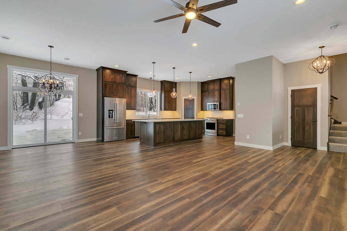A large empty room with hardwood floors and a ceiling fan.