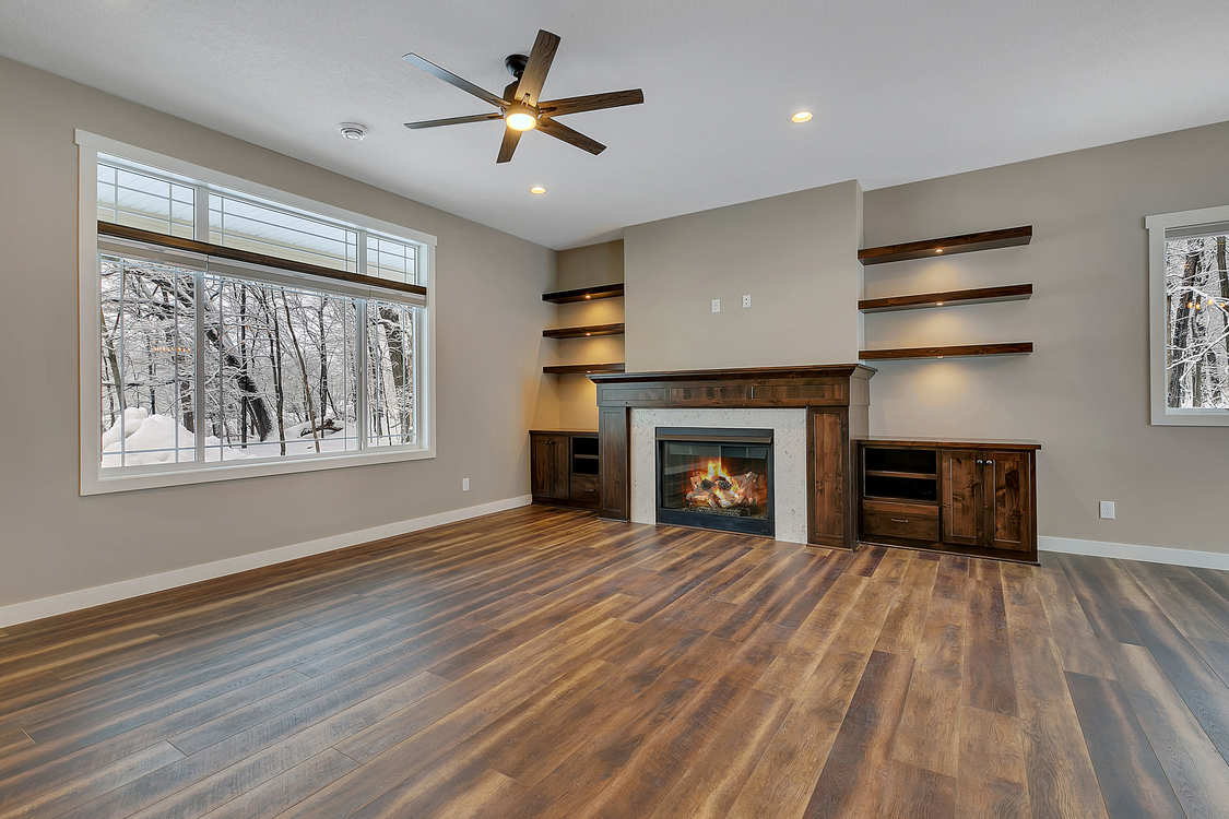 A living room with hardwood floors , a fireplace and a ceiling fan.