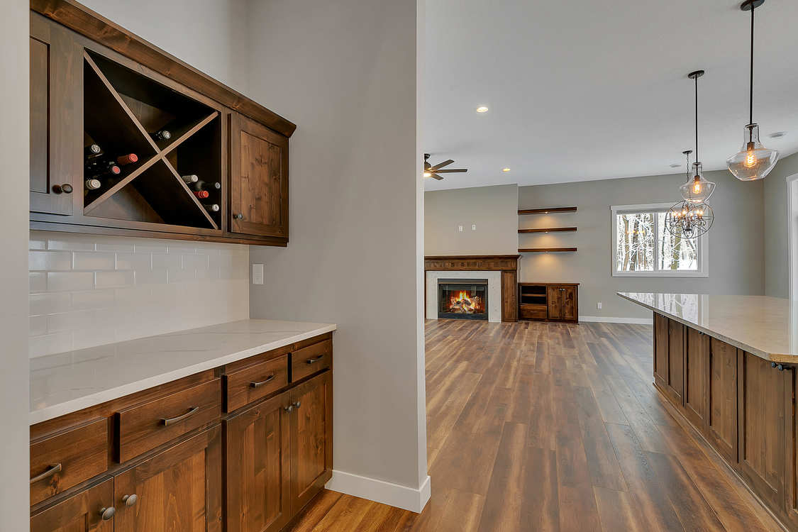 A kitchen with wooden cabinets , a wine rack and a fireplace.
