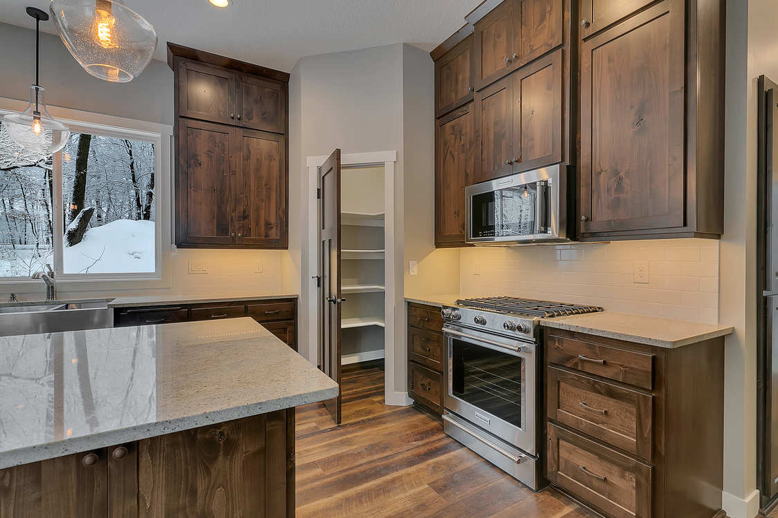 A kitchen with wooden cabinets , granite counter tops , stainless steel appliances and a large island.