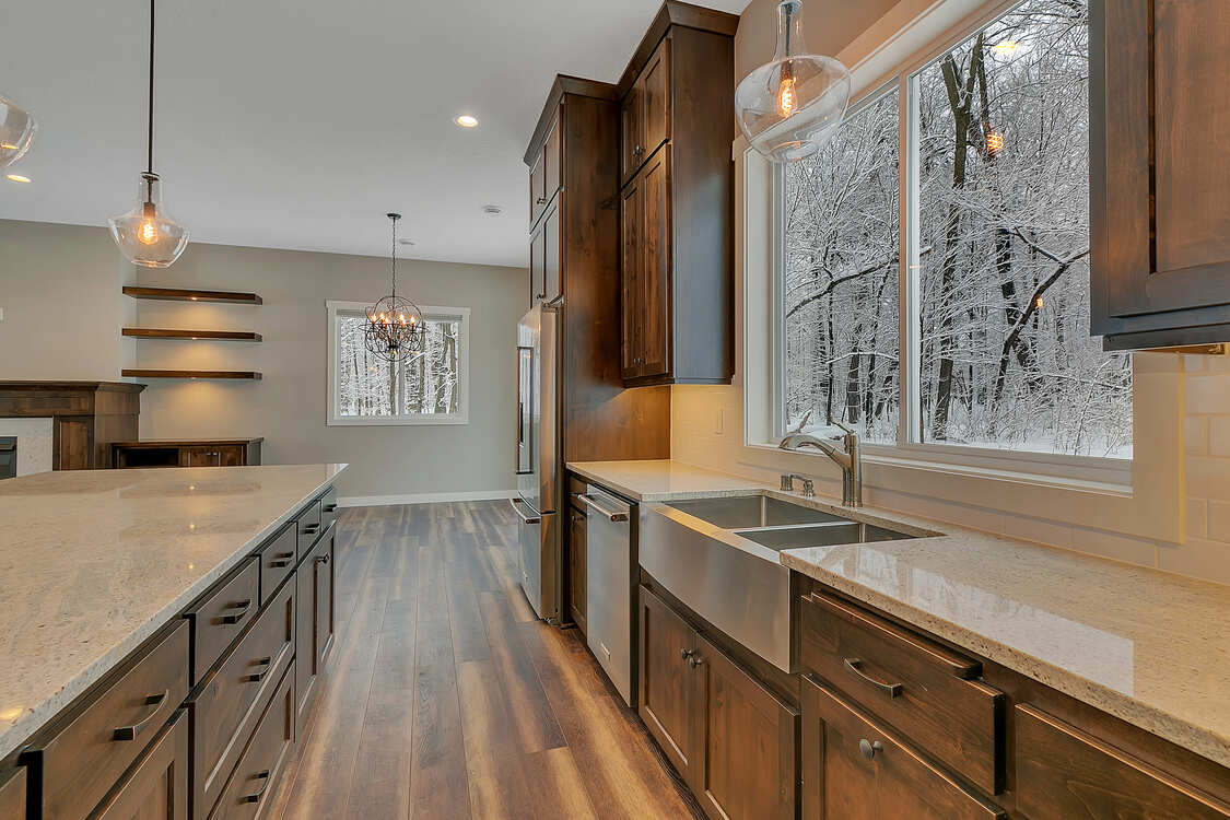 A kitchen with wooden cabinets , granite counter tops , a sink and a large window.