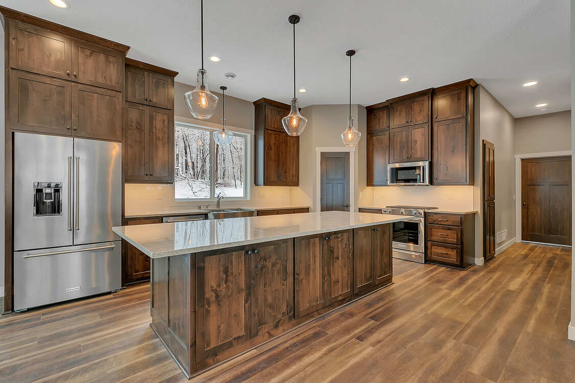 A kitchen with wooden cabinets , stainless steel appliances , and a large island.