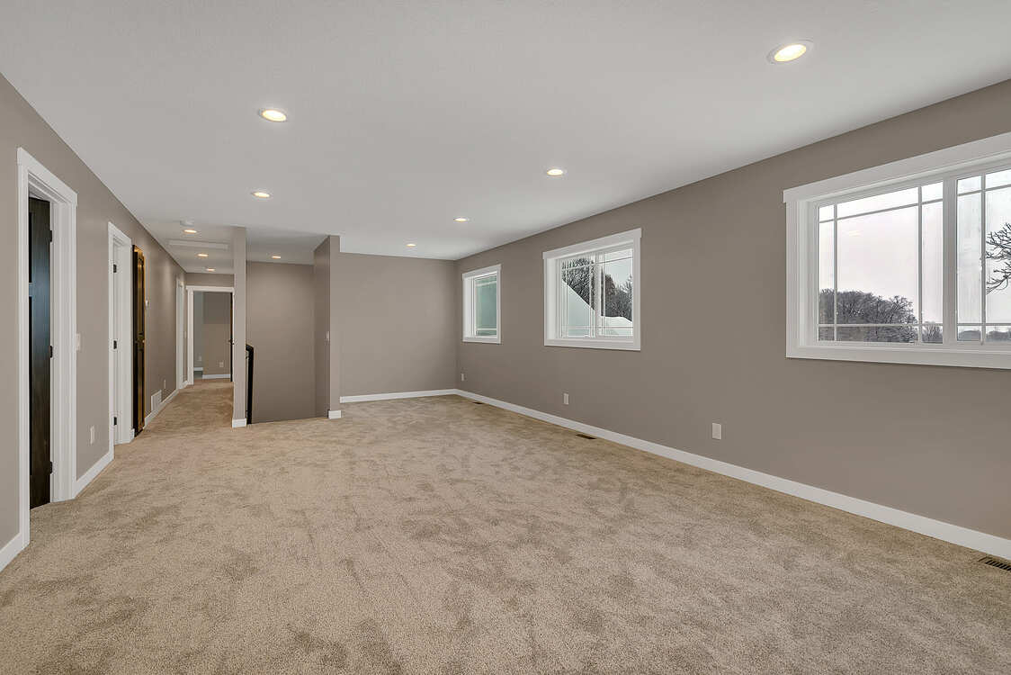A large empty room with a lot of windows and carpet.