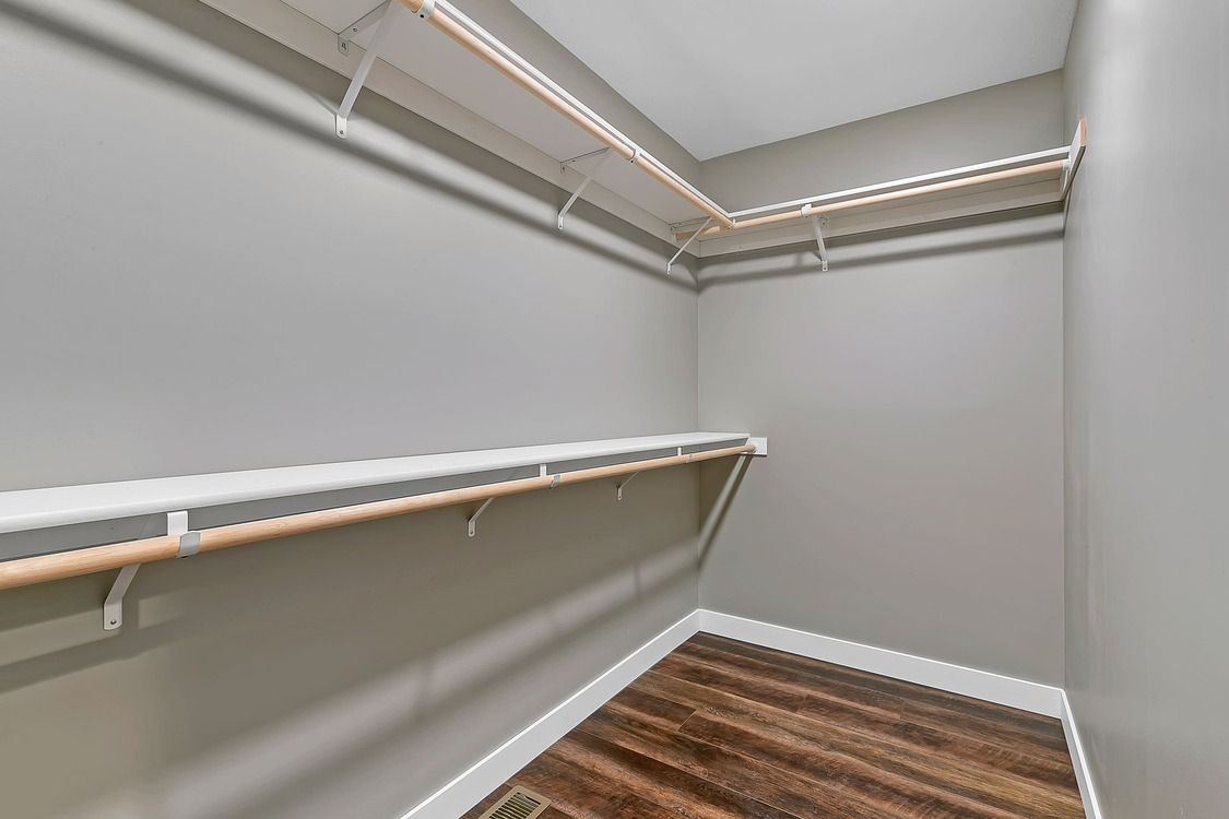 An empty walk in closet with wooden floors and shelves.