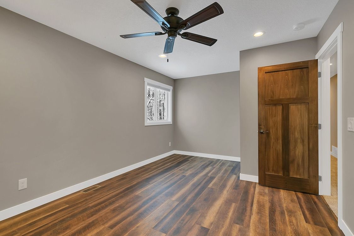 An empty room with hardwood floors and a ceiling fan.