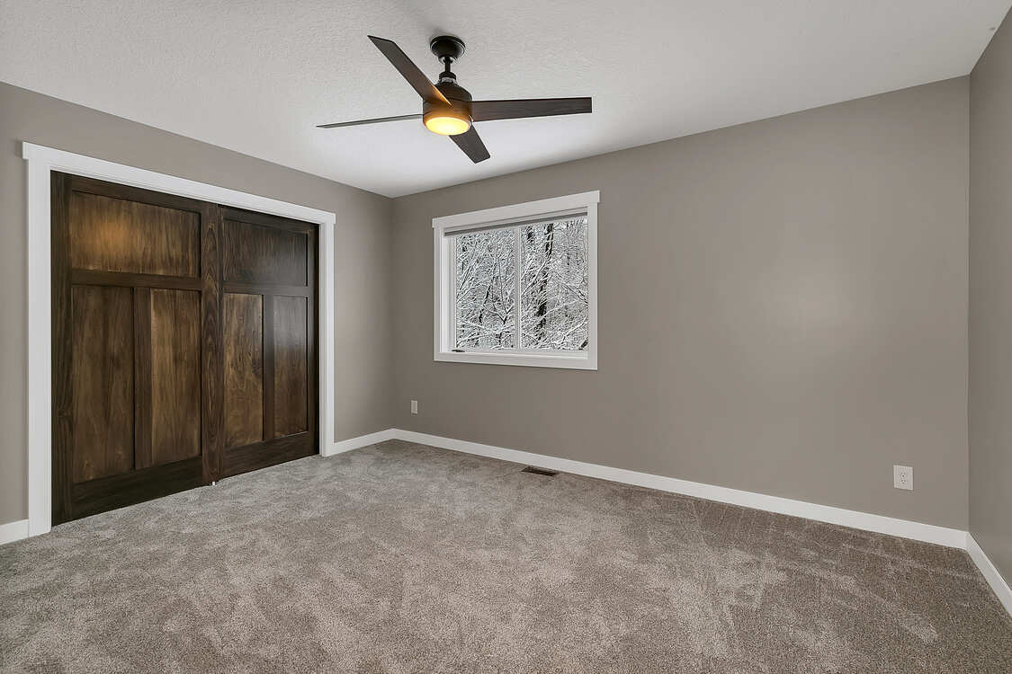 An empty bedroom with a ceiling fan and a window.