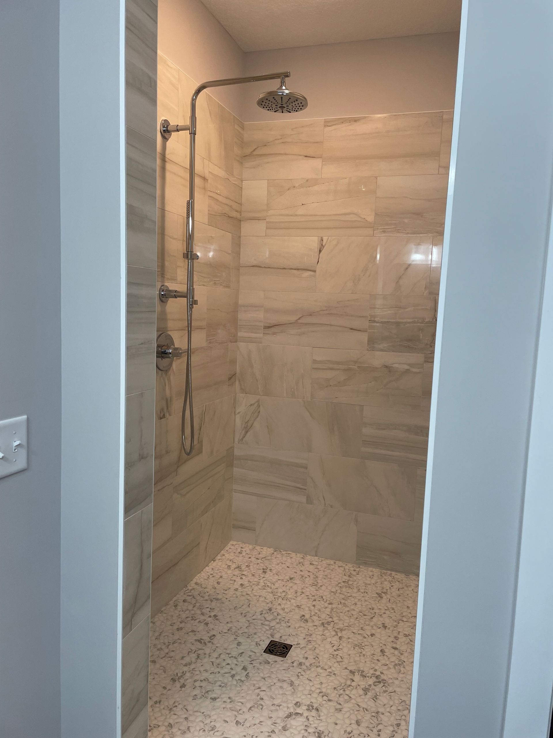 A bathroom with a walk in shower and a shower head.
