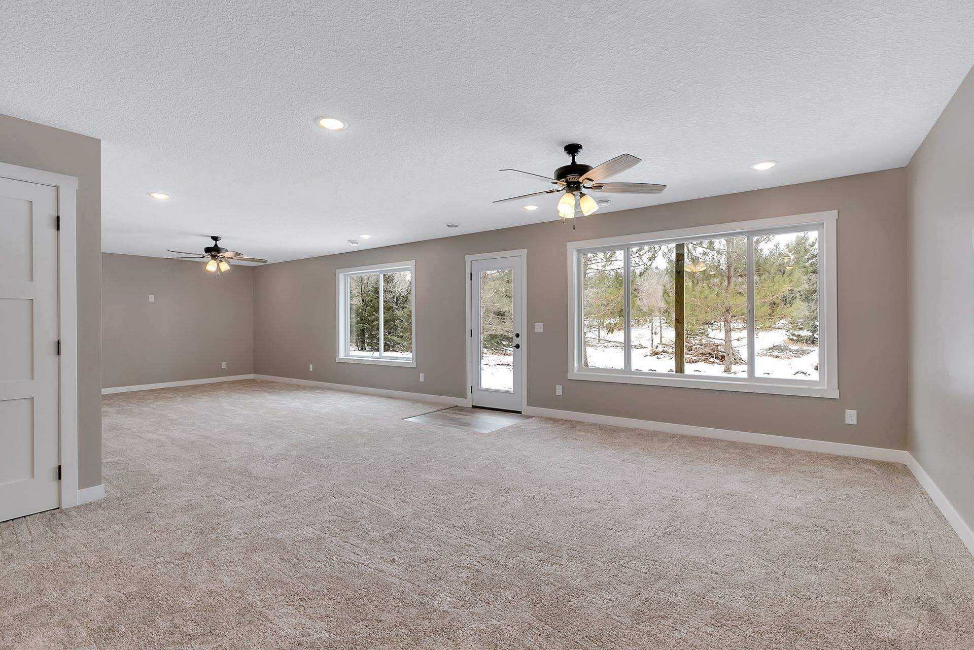 A large empty room with a lot of windows and a ceiling fan.