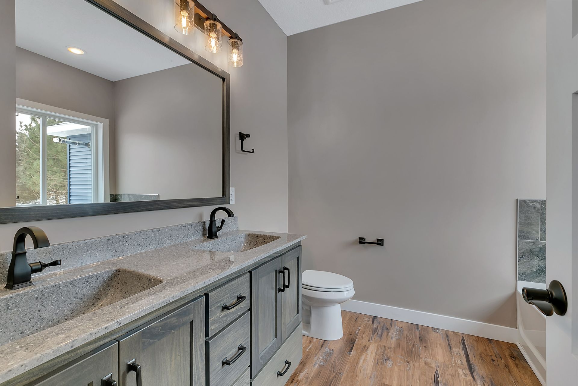 A bathroom with two sinks , a toilet , and a large mirror.