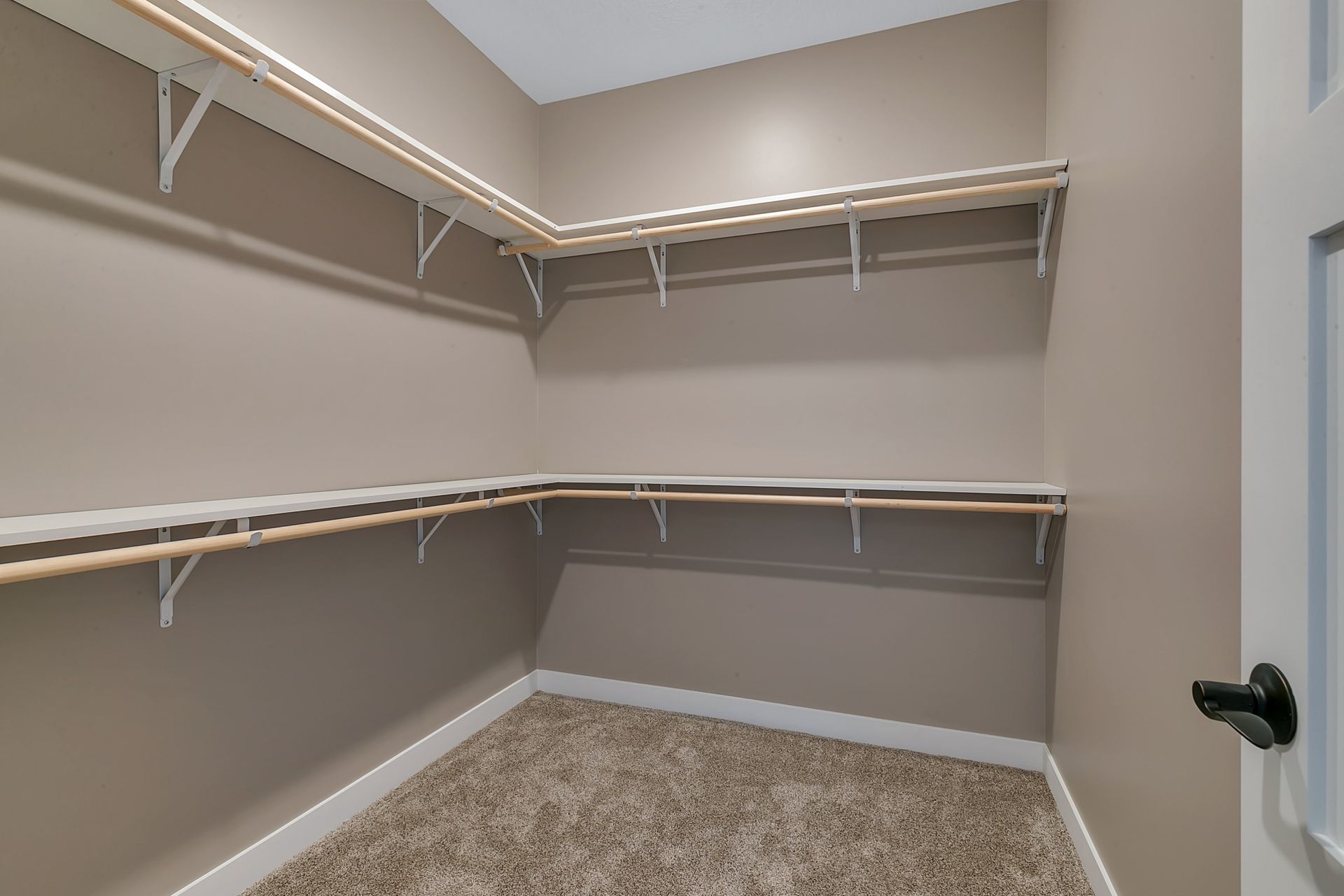 An empty walk in closet with shelves and a door.
